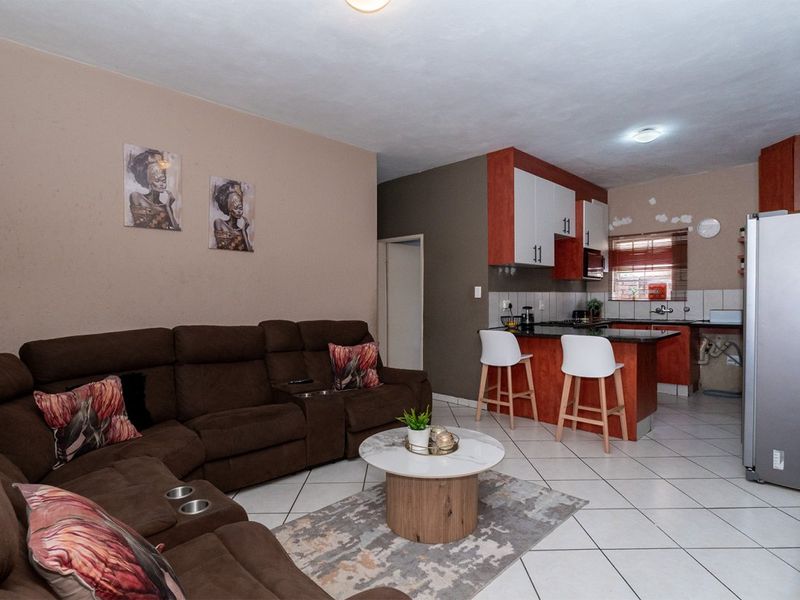 Open-plan living area featuring a kitchen with granite countertops, breakfast bar, and tiled flooring throughout the combined space.