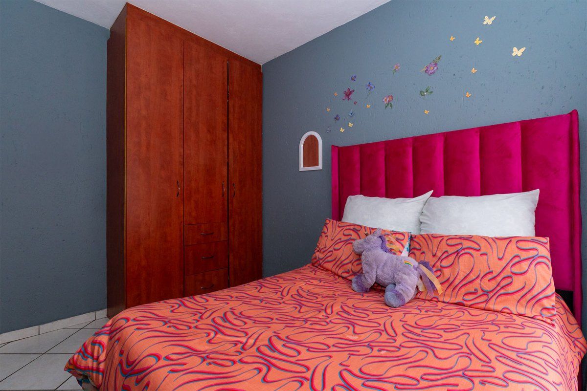 A bedroom featuring a built-in wooden wardrobe and tiled flooring, finished with blue painted walls.