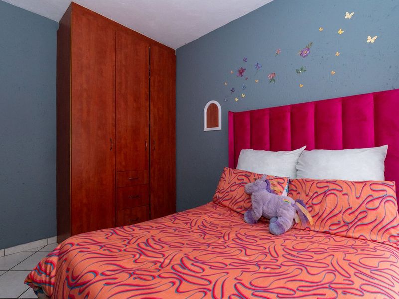 A bedroom featuring a built-in wooden wardrobe and tiled flooring, finished with blue painted walls.