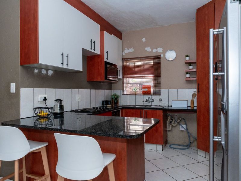 Compact kitchen featuring granite countertops, built-in cabinetry, and tiled flooring, currently requiring cosmetic repairs to walls and ceiling finishes.