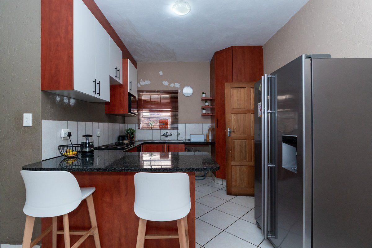 A compact kitchen featuring granite countertops, two-tone cabinetry, and tiled flooring, requiring minor cosmetic repairs to the wall finishes.