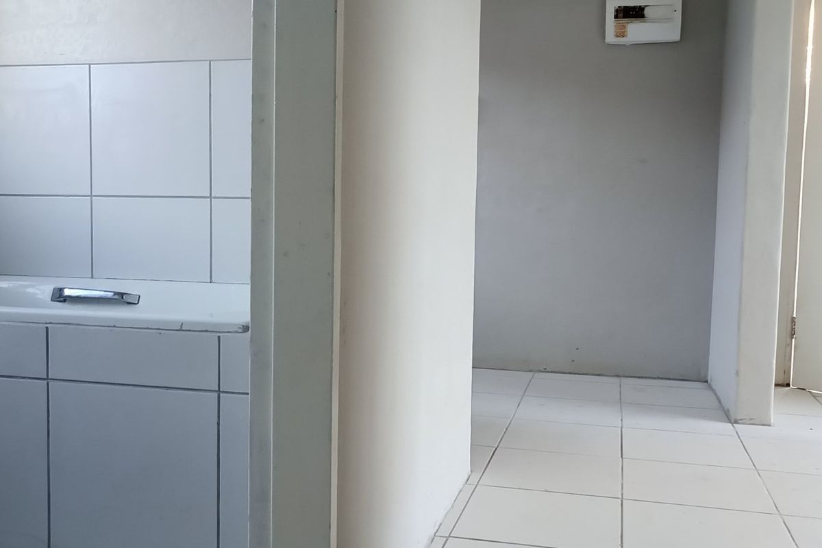 A view of a bathroom featuring a tiled bathtub and adjacent hallway area with neutral wall finishes and ceramic floor tiles.