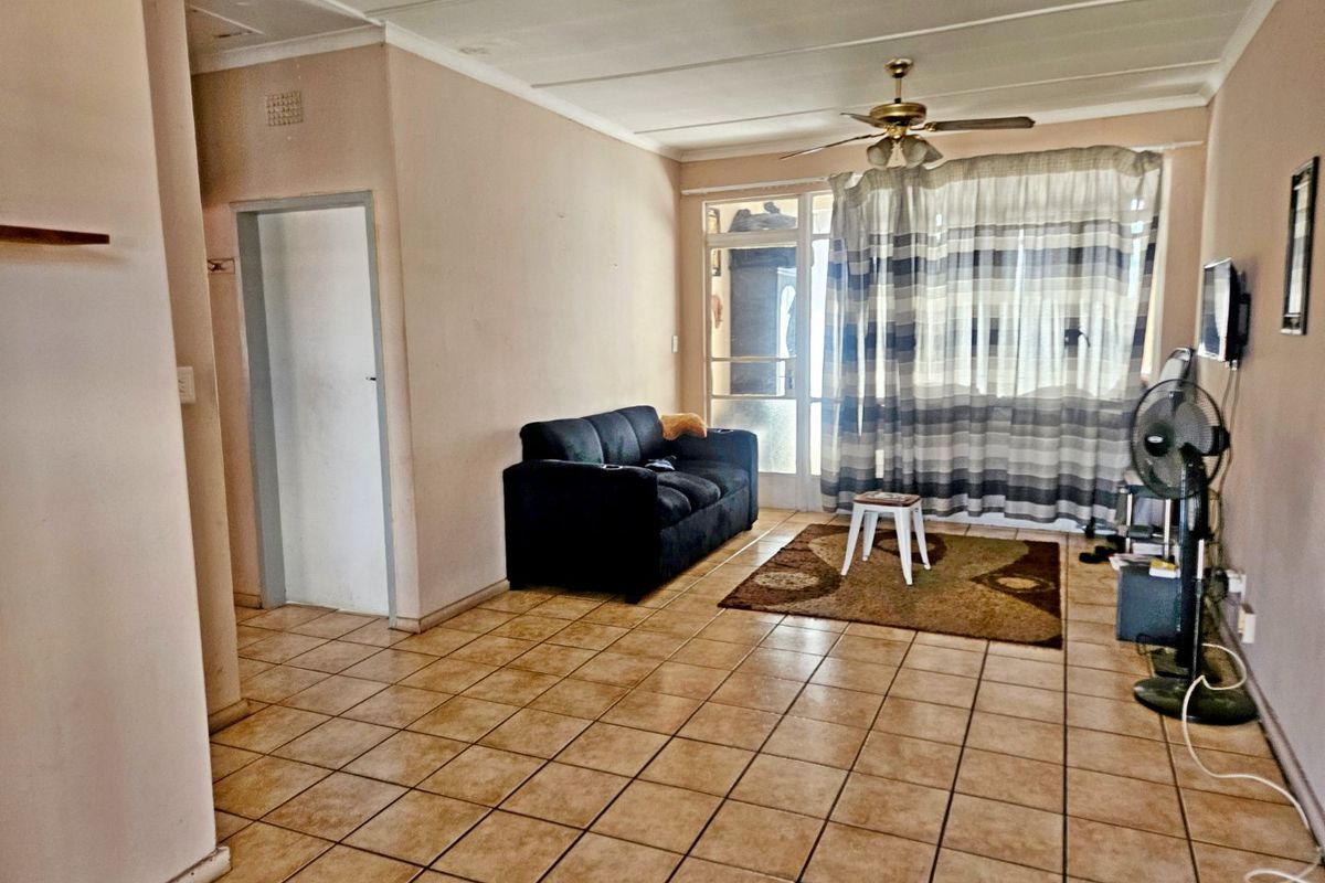 A living room featuring ceramic floor tiles, a ceiling fan, and a sliding glass door providing access to the exterior.
