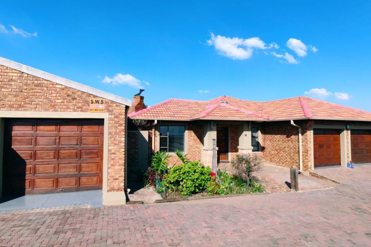 Front view of a face-brick residential property featuring a tiled roof, double garage, and paved driveway.