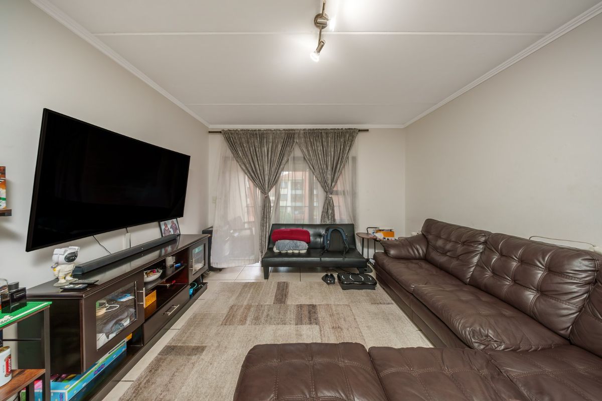 A functional living room featuring tiled flooring, a ceiling-mounted spotlight fixture, and a sliding glass door providing access to the exterior.
