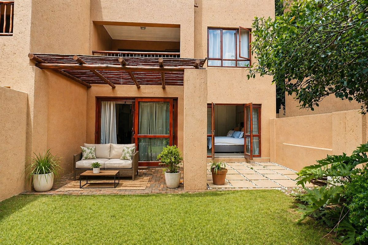 A private rear garden featuring a paved patio area with a timber pergola, accessible via sliding doors from the interior living and bedroom spaces.