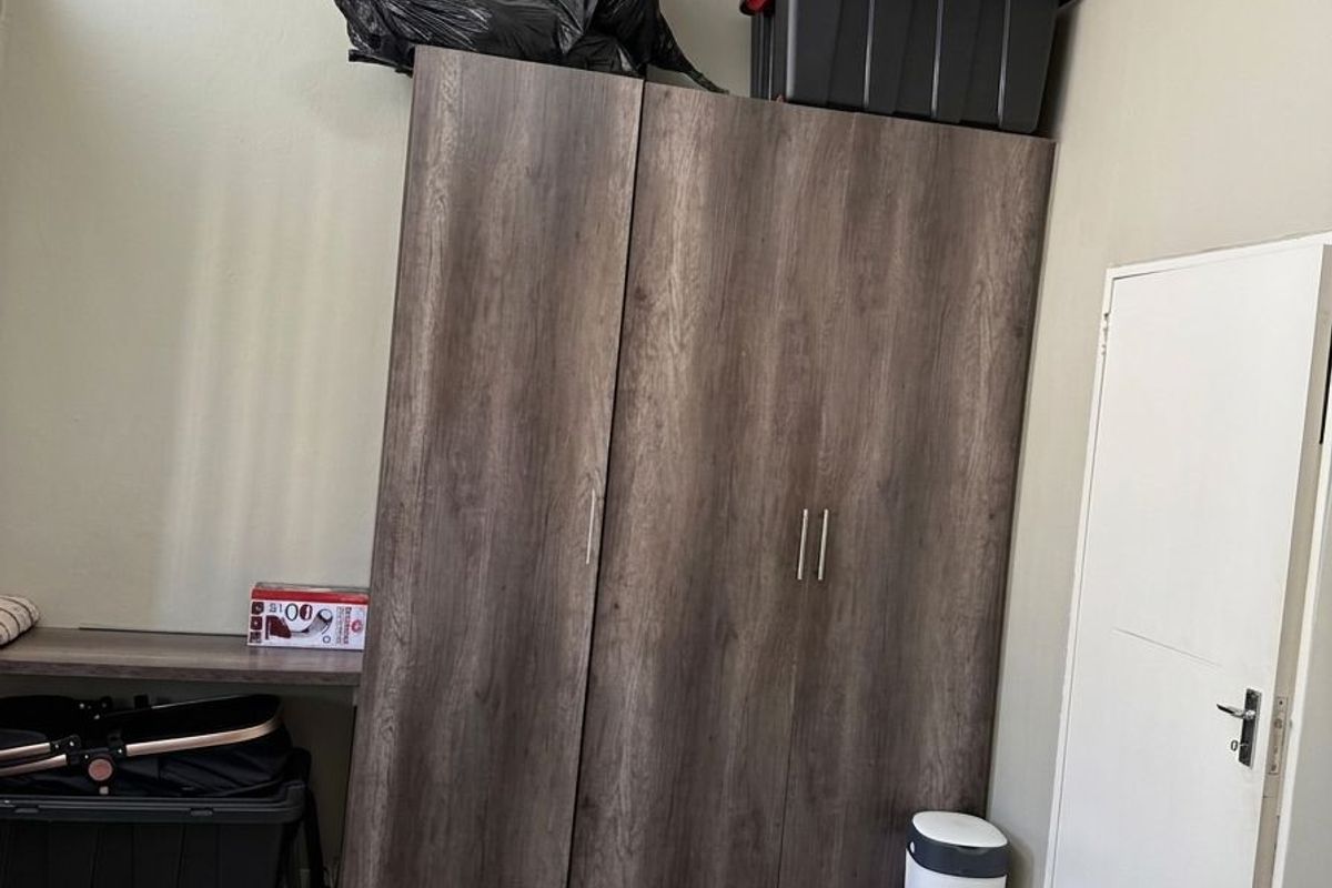 A bedroom featuring tiled flooring and a large built-in wooden wardrobe, providing ample storage space within the room.
