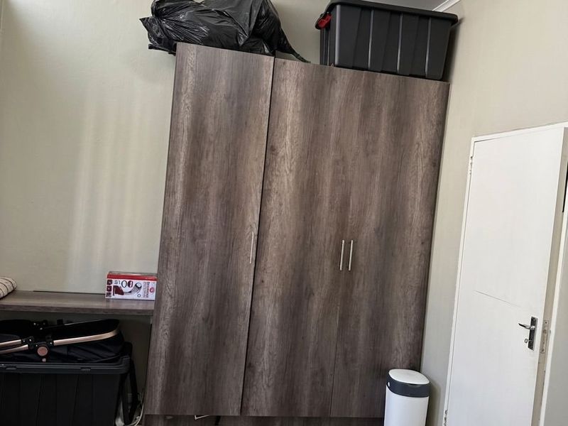 A bedroom featuring tiled flooring and a large built-in wooden wardrobe, providing ample storage space within the room.