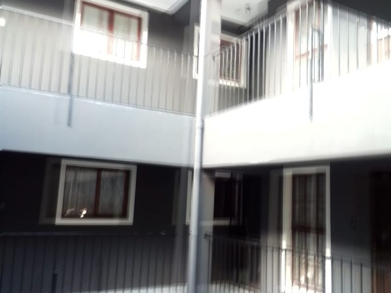 A view of the apartment building's exterior walkways and metal balustrades, showing the multi-level structure and window placements.