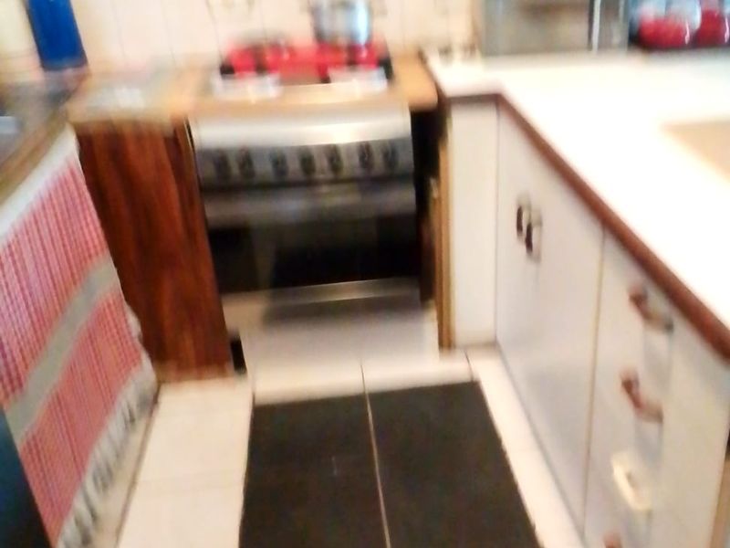 A compact kitchen featuring a built-in oven, cooktop, tiled backsplash, and laminate countertops with fitted cabinetry.