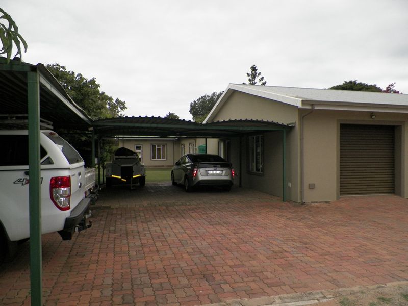 Front exterior view featuring a paved driveway, a covered carport area, and a single garage with a roller shutter door.