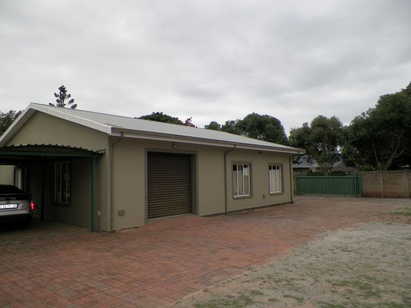 Front exterior view of the property featuring a paved driveway, attached carport, roller garage door, and perimeter fencing.