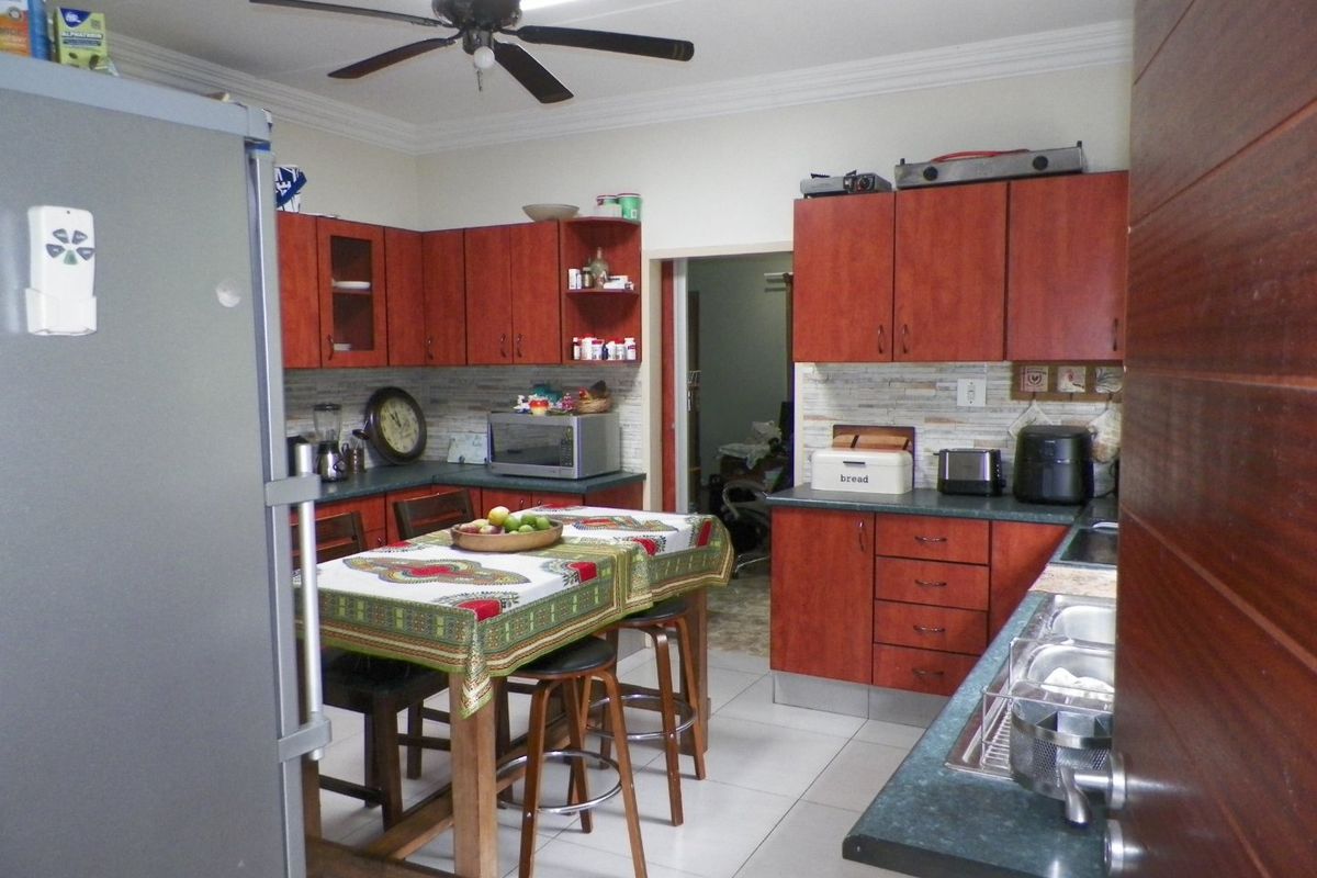 A functional kitchen featuring wood-tone cabinetry, stone-look countertops, tiled backsplash, and a ceiling fan, offering a practical layout for daily meal preparation.