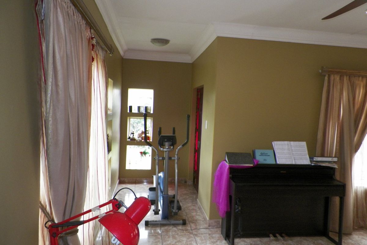 A living area featuring tiled flooring, cove cornicing, and recessed wall shelving, currently utilized as a multi-purpose space.