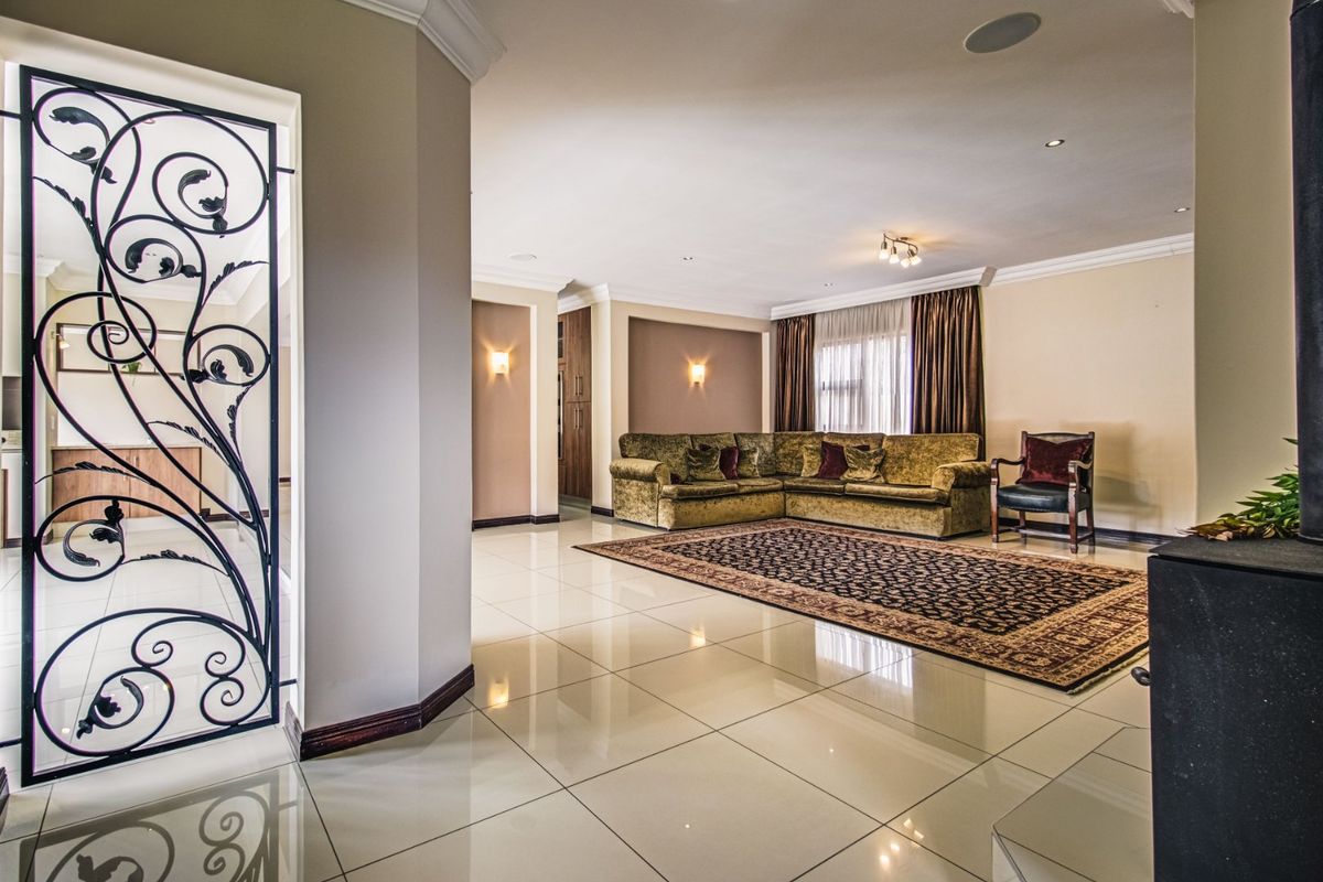 Spacious living area featuring polished tiled flooring, recessed lighting, wall sconces, and a decorative wrought iron feature gate.