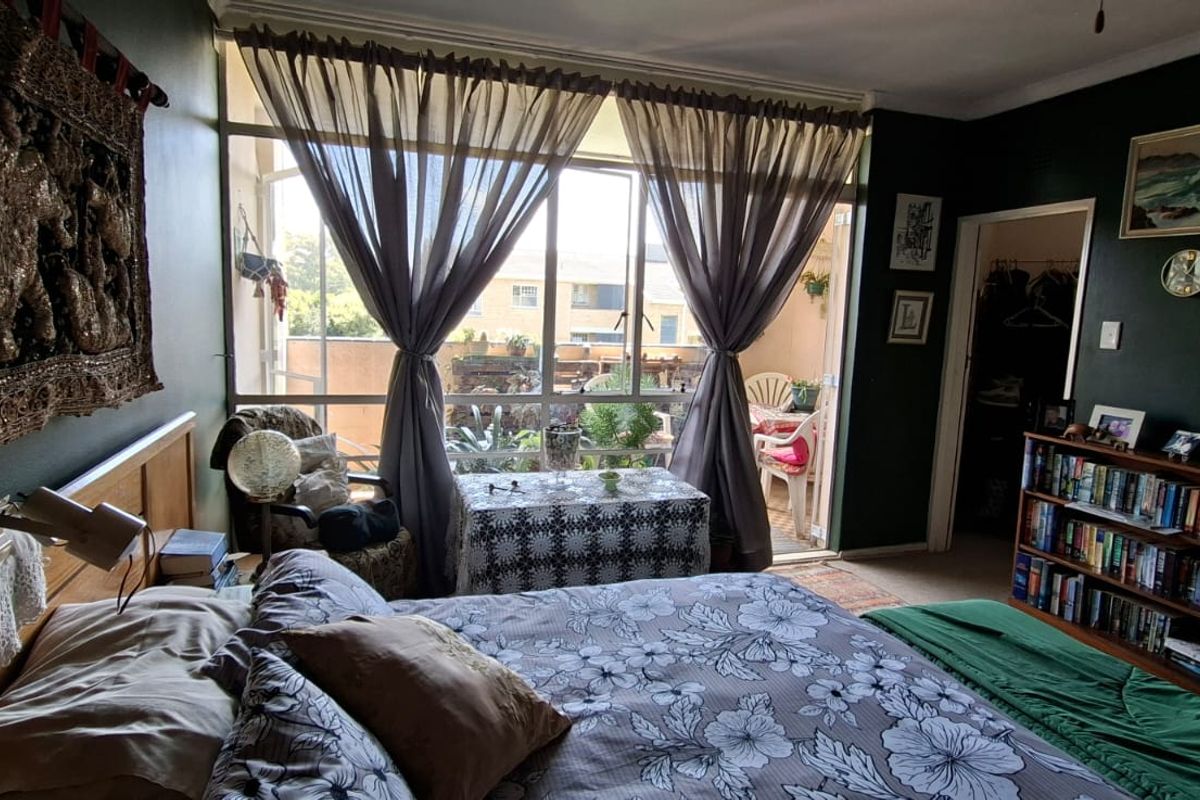 A bedroom featuring dark green walls, built-in storage, and a large glass sliding door providing access to an attached balcony.