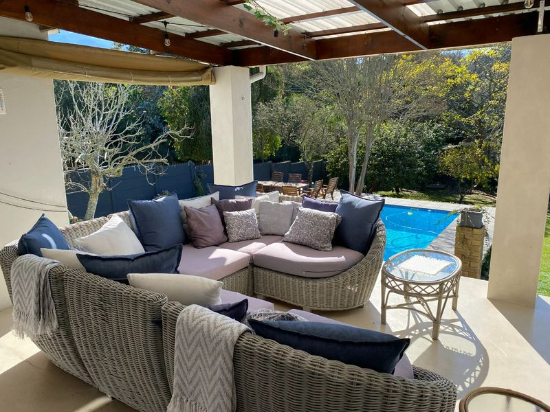 Covered patio area featuring a timber pergola, overlooking a private swimming pool and landscaped garden.