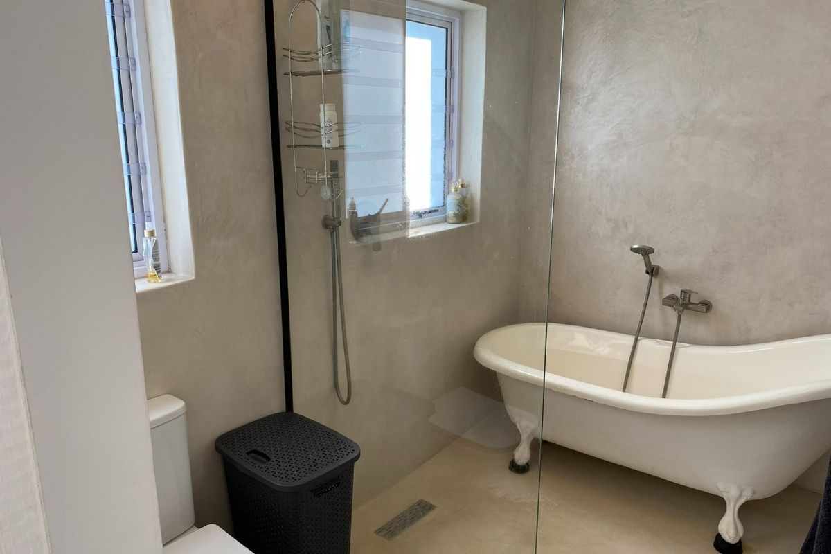 Modern bathroom featuring a freestanding clawfoot bathtub, a walk-in shower with a glass screen, and contemporary tadelakt wall finishes.