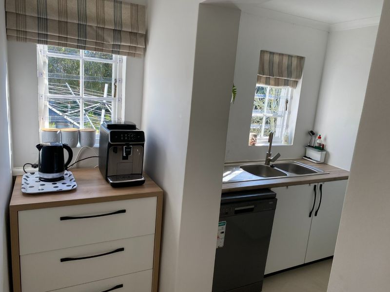 A functional scullery area featuring a double bowl sink, modern cabinetry, laminate countertops, and an integrated dishwasher, providing additional prep and wash-up space.