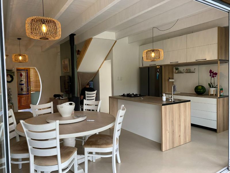 Modern open-plan living and kitchen area featuring a central island, gas hob, exposed beam ceilings, and a cozy fireplace.