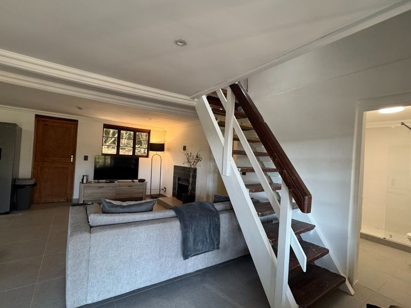 Open plan living area featuring a fireplace, tiled flooring, and a wooden staircase leading to the upper level.