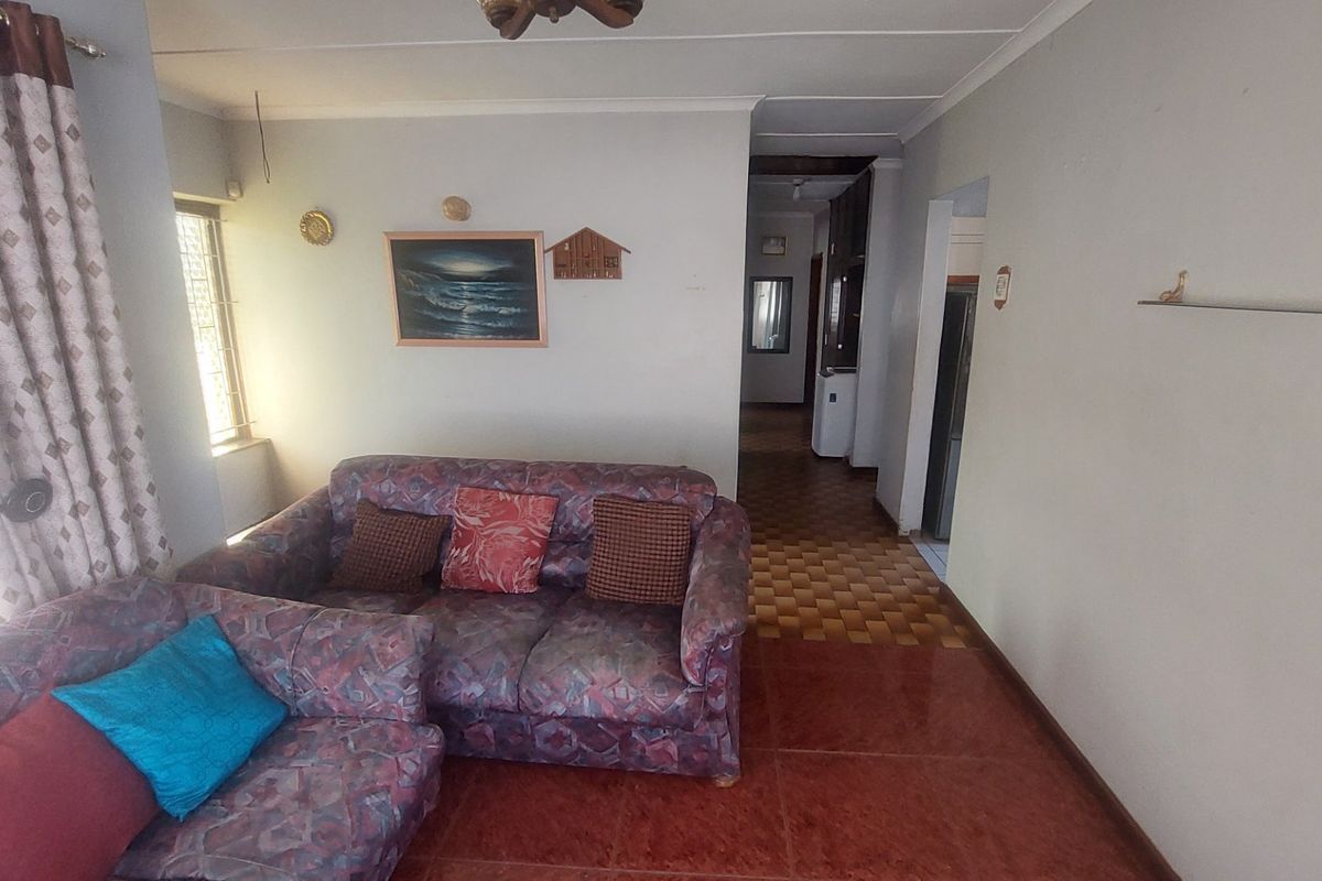 A living room area featuring tiled flooring and access to an internal hallway, showing dated finishes and potential for modernization.