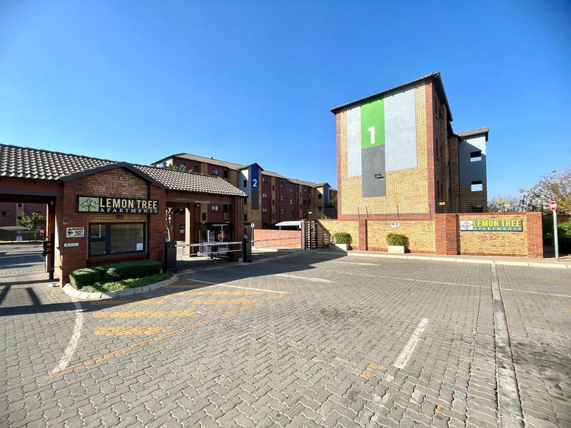 The entrance to Lemon Tree Apartments featuring a secure gated access point, brick-paved driveway, and clearly marked apartment blocks.