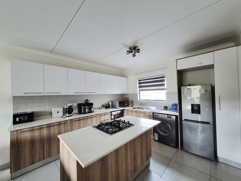 Modern kitchen featuring a central island with a gas hob, ample built-in cabinetry, stone countertops, and tiled flooring.