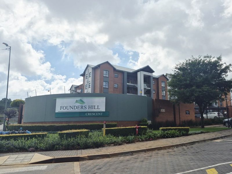 Front exterior view of Founders Hill Crescent apartment complex featuring brick architecture, secure perimeter fencing, and well-maintained landscaped grounds.