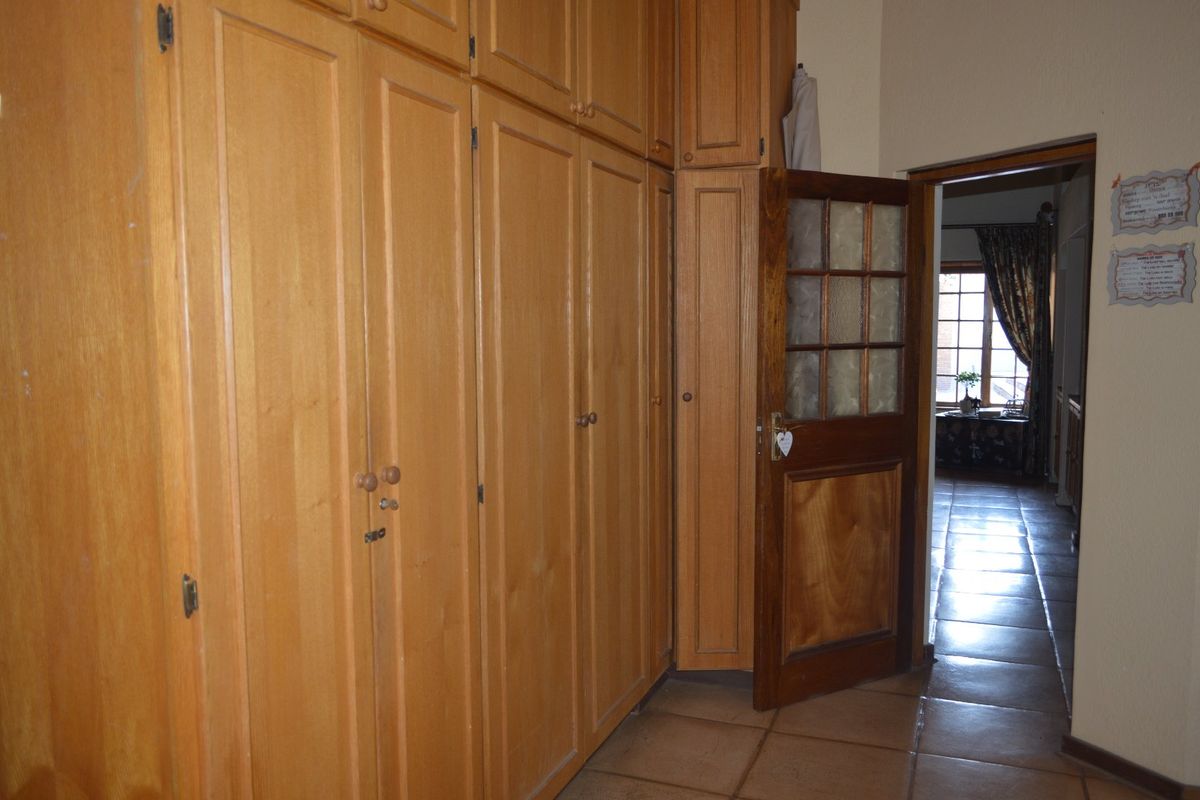 Bedroom featuring extensive built-in wooden cabinetry, tiled flooring, and a classic wooden door leading to an adjacent room.