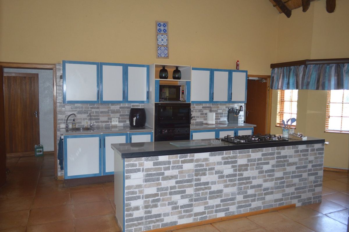 A functional kitchen featuring built-in cabinetry, a gas hob, integrated oven, and a central island with a stone-look tiled finish.