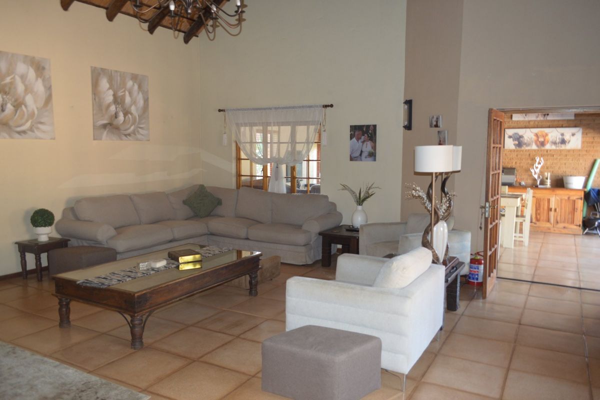 Spacious living room featuring exposed timber ceiling beams and ceramic floor tiles, with an open transition to the adjacent dining area.