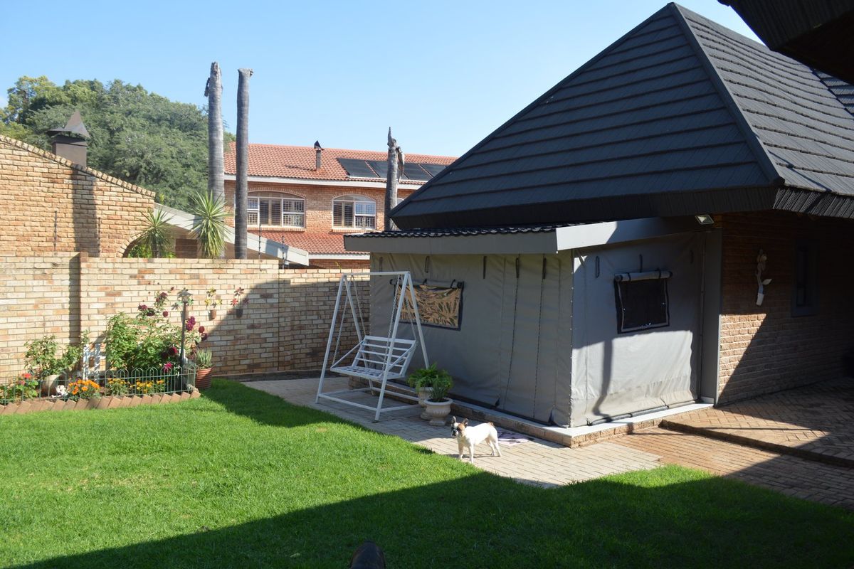 Rear garden area featuring a paved patio, enclosed outdoor structure, and brick boundary walling.