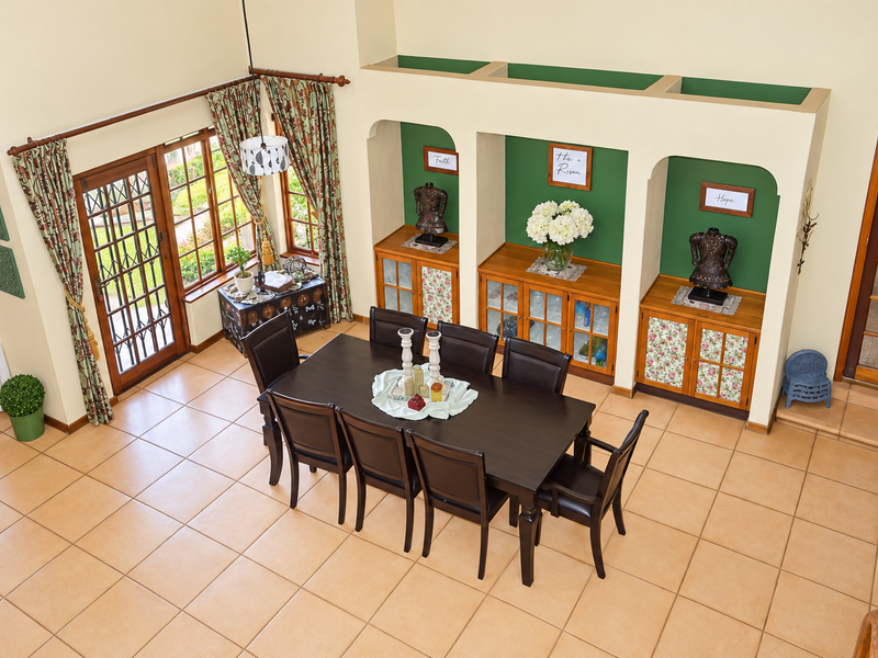 Spacious dining room featuring high vaulted ceilings, tiled flooring, and unique arched wall niches with built-in cabinetry, offering a bright and inviting atmosphere.