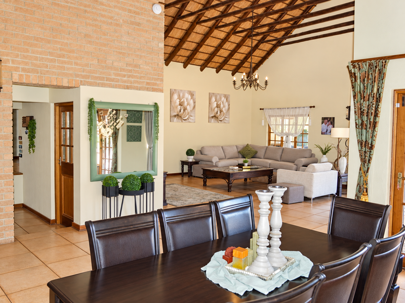 Spacious open-plan living and dining area featuring a high vaulted thatched ceiling with exposed timber beams and classic brick feature walling.