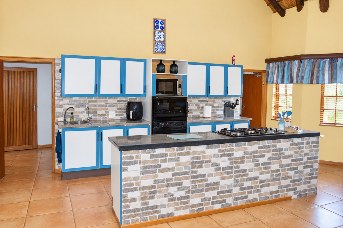 Spacious kitchen featuring a central island with a gas cooktop, built-in oven, microwave, stone countertops, and tiled finishes under a high vaulted ceiling.
