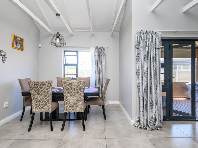 Bright dining room featuring exposed beam ceilings, large format floor tiles, and direct access to an outdoor patio area through sliding doors.