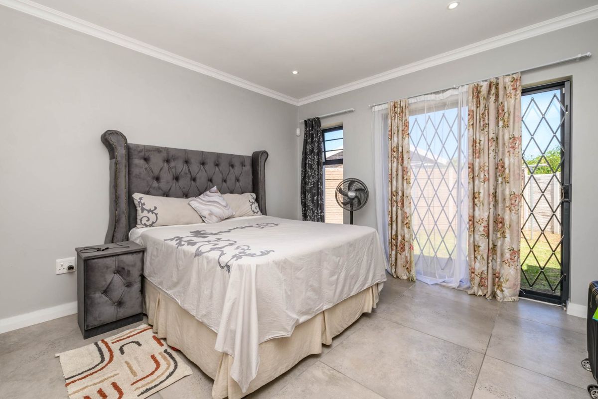 A well-maintained bedroom featuring large format floor tiles, recessed lighting, and a sliding glass door providing direct access to the rear garden.
