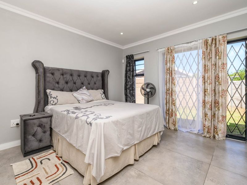 A well-maintained bedroom featuring large format floor tiles, recessed lighting, and a sliding glass door providing direct access to the rear garden.
