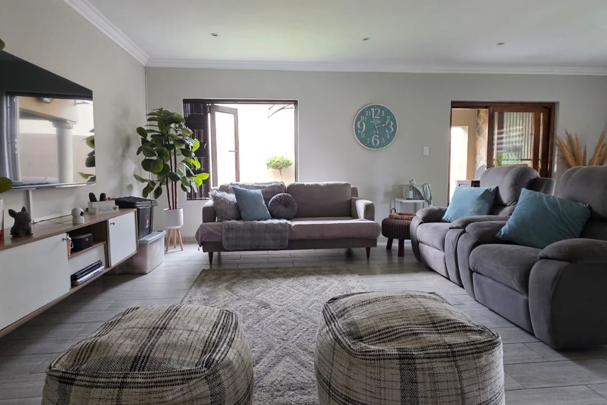 A comfortable and well-maintained living room featuring tiled flooring, recessed downlighting, and access to an outdoor area through a sliding door.