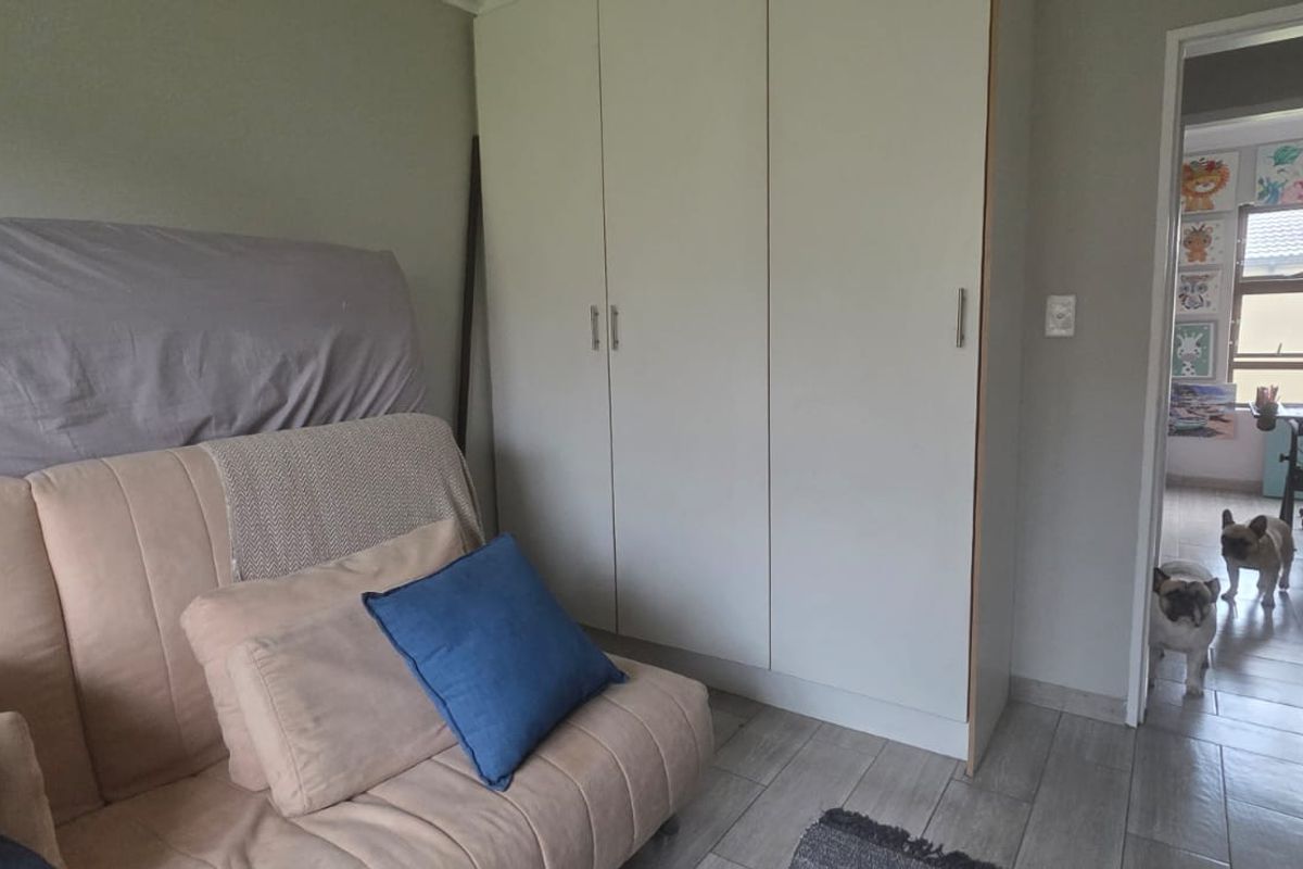 A bedroom featuring built-in cupboards and tiled flooring, with a doorway leading to an adjacent room.