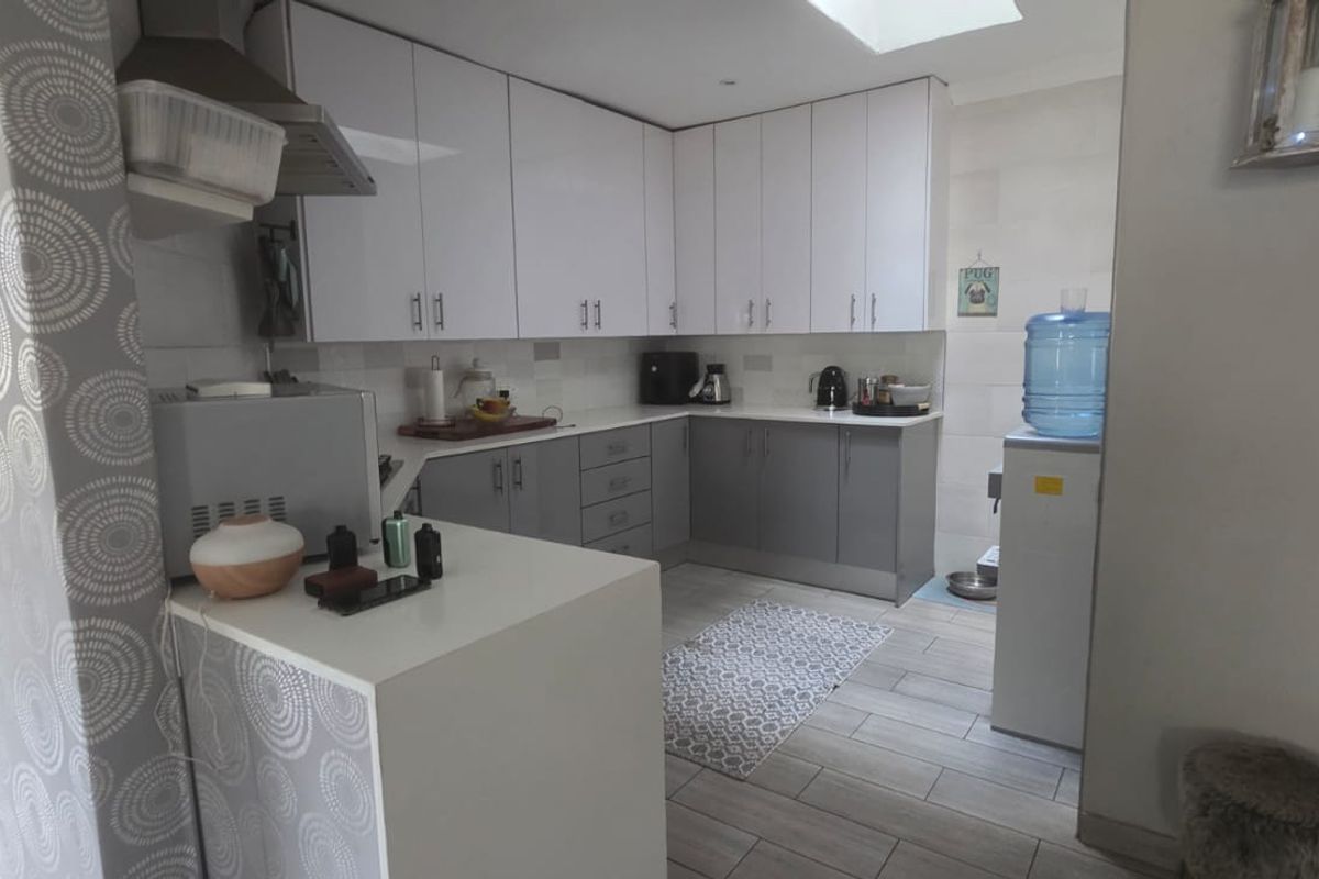A modern kitchen featuring two-tone cabinetry, tiled flooring, and a skylight, providing a functional and bright workspace.