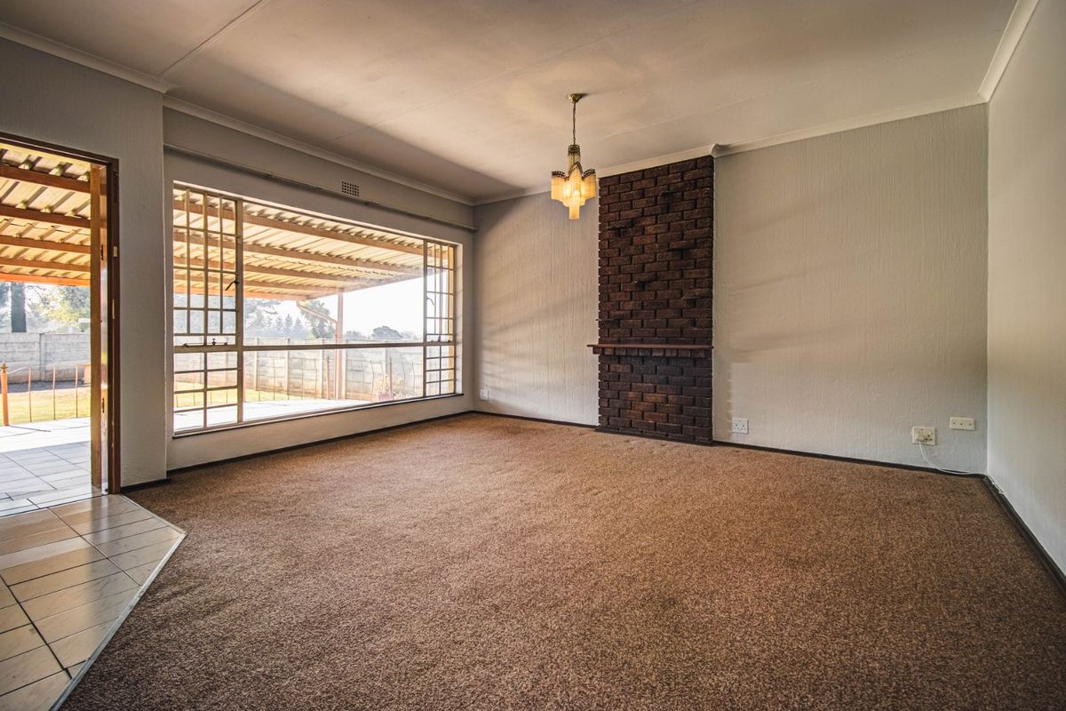 Spacious living room featuring a brick fireplace, large window with natural light, and carpet flooring, offering direct access to the outdoor patio area.
