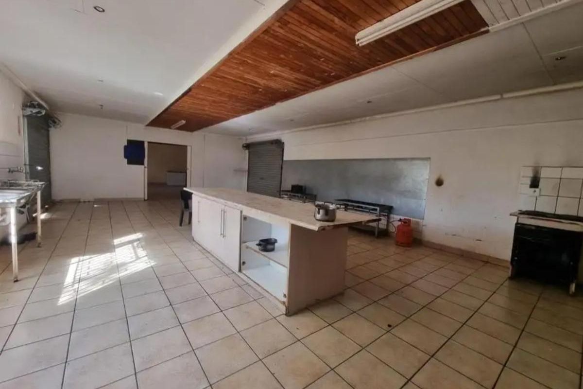 Spacious kitchen area featuring a central island, tiled flooring, and wood-paneled ceiling detail, offering a functional layout for a farm property.