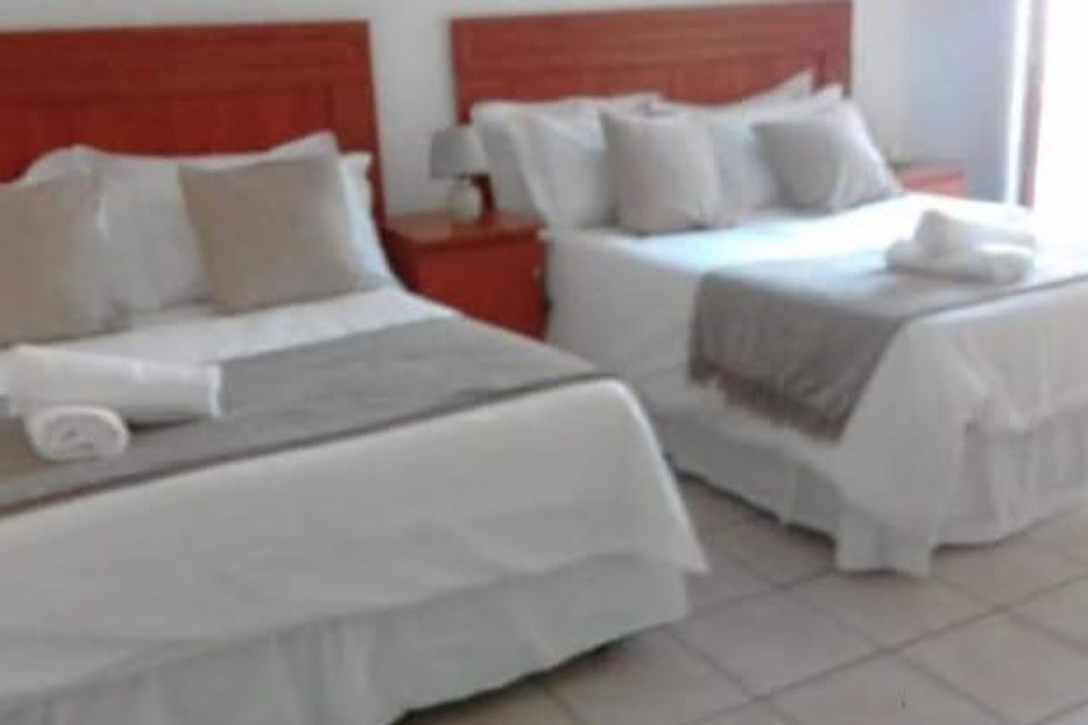 A bedroom featuring tiled flooring and two beds with wooden headboards.