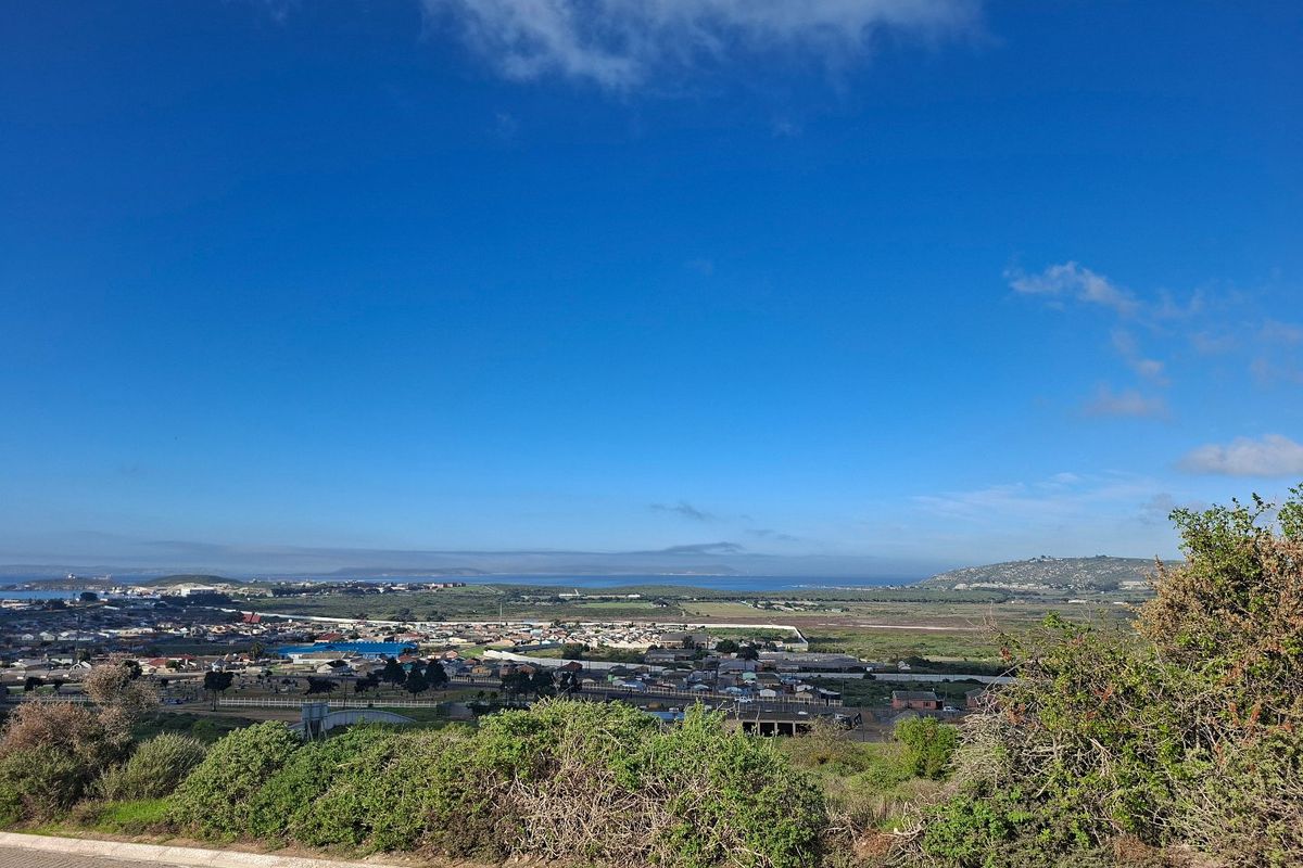 A wide-angle elevated view overlooking the surrounding residential landscape and distant coastline under a clear blue sky.