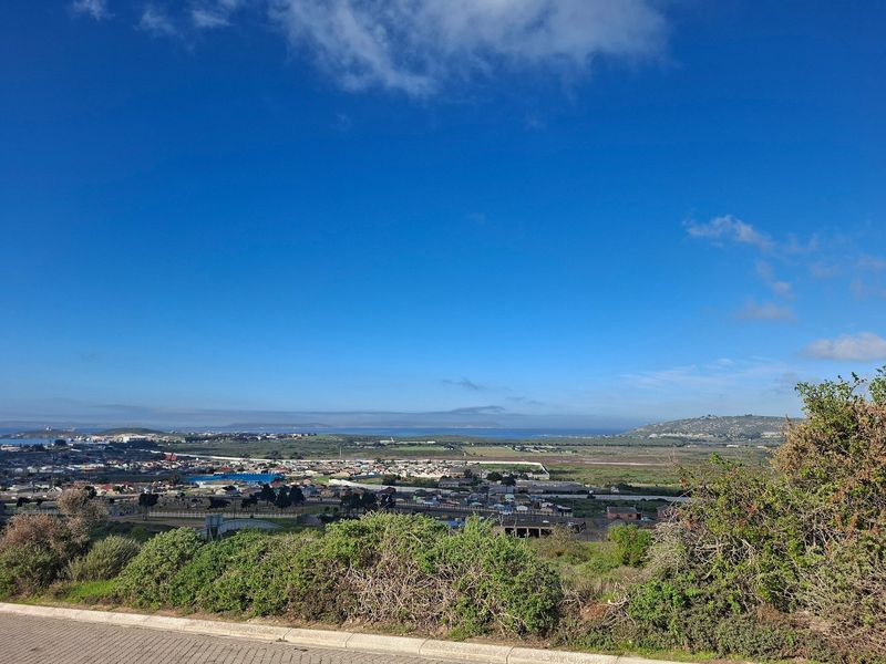 A wide-angle elevated view overlooking the surrounding residential landscape and distant coastline under a clear blue sky.