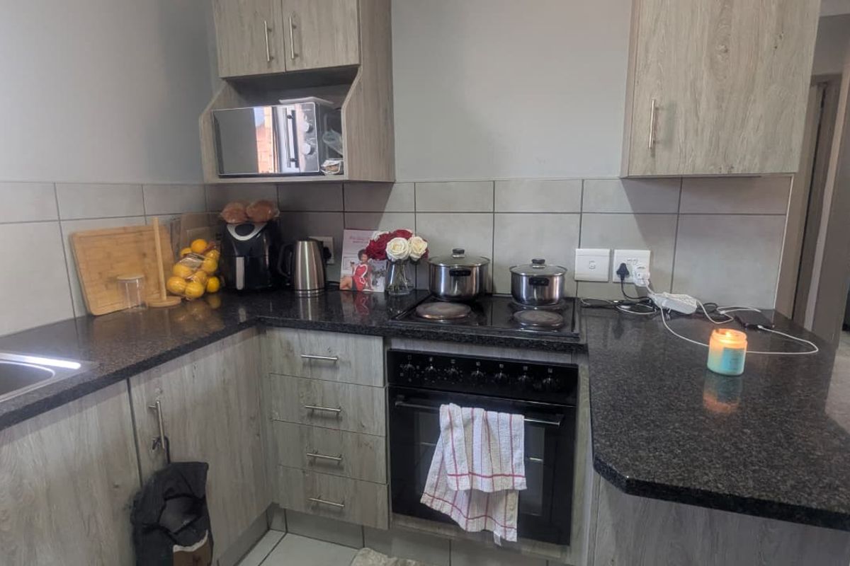 A functional kitchen featuring wood-look cabinetry, granite countertops, a built-in oven with electric hob, and a tiled backsplash.