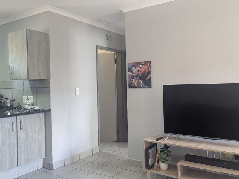Open plan living area featuring tiled flooring and a compact kitchen with laminate cabinetry and granite countertops.