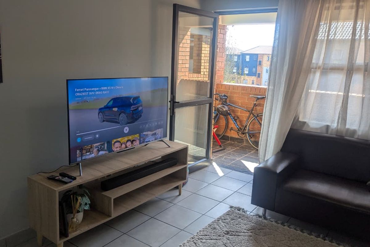 A living room area featuring tiled flooring and direct access to an outdoor balcony through a sliding glass door.